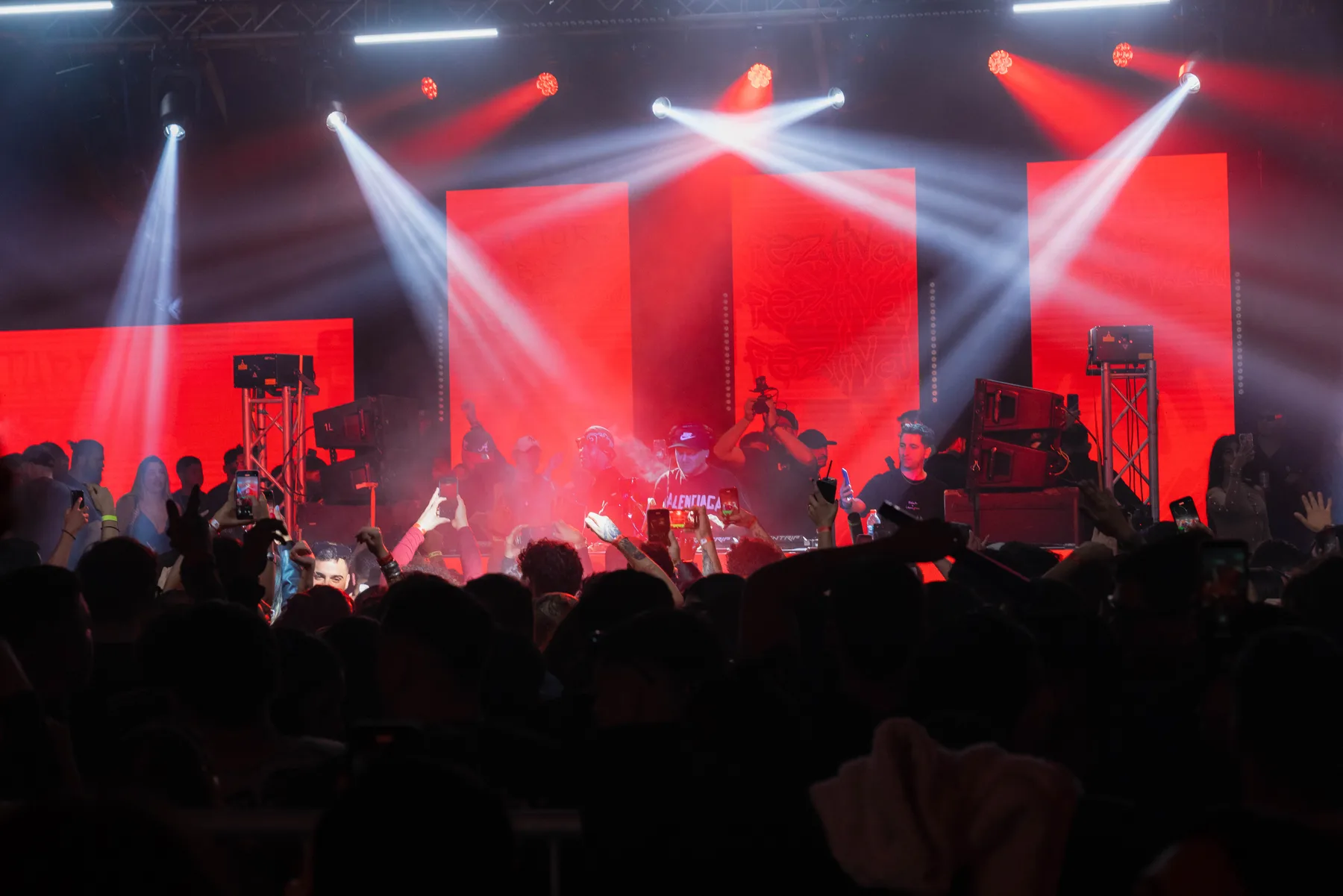 Escenario con pantallas LED rojas y haces de luz sobre el público en FEZTIVAL