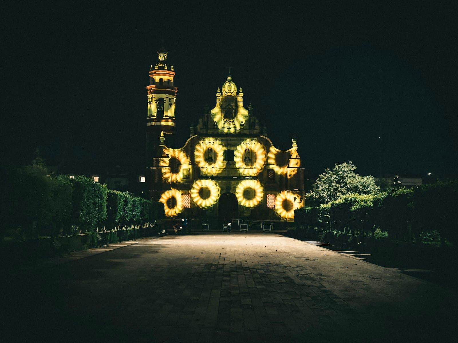 Flores de luz proyectadas sobre iglesia colonial de noche